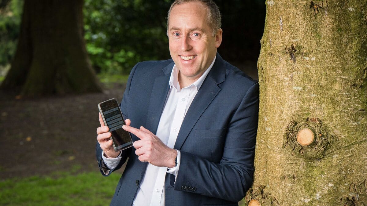 Alan Craughwell, founder of AssistiV Ireland, holding a phone with the AssistiV app