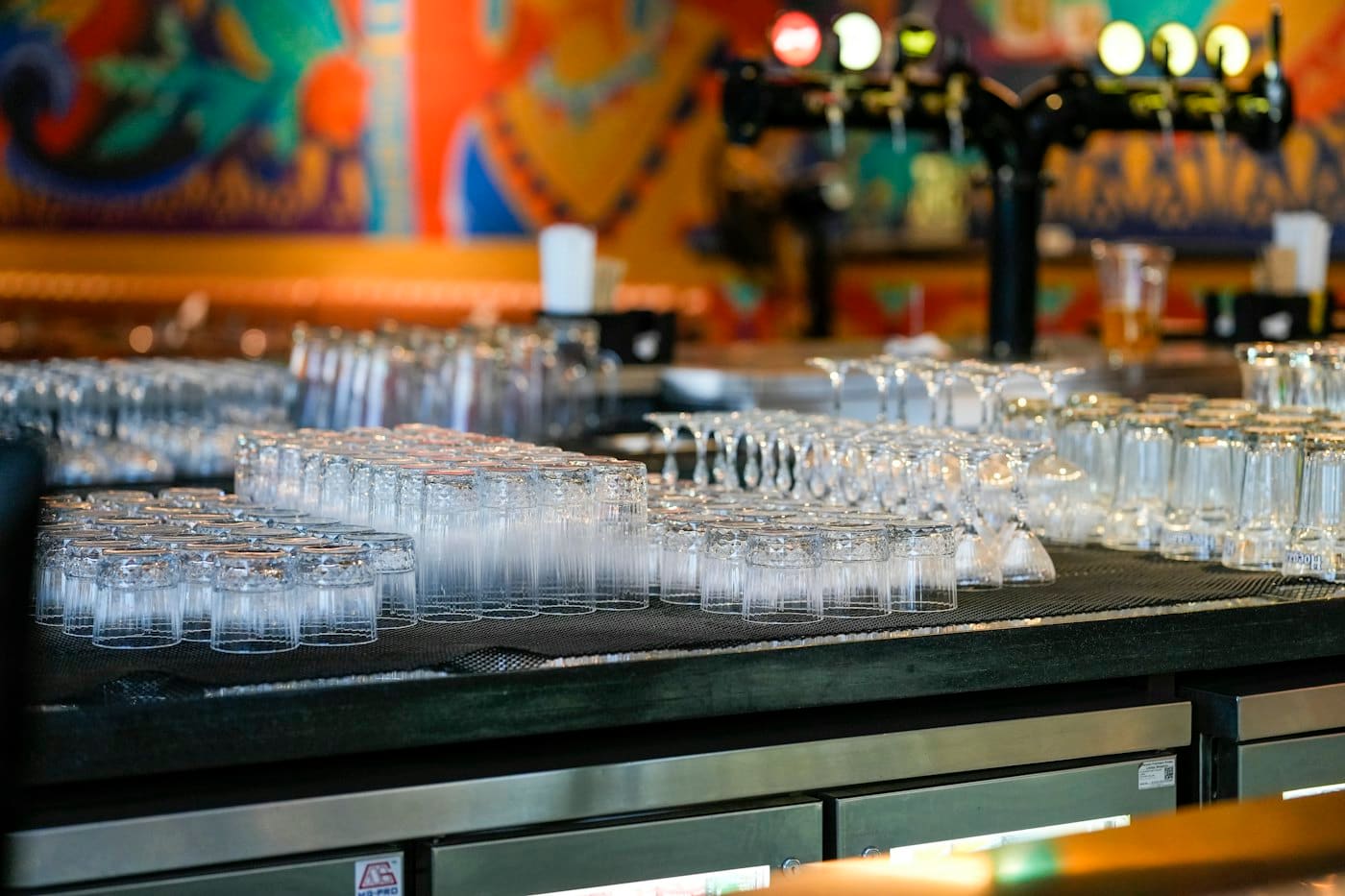Clean glasses on a bar counter beside the beer taps